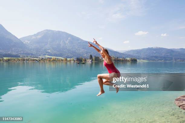 austria, alps, salzburg, salzkammergut, salzburger land, wolfgangsee, woman jumping into lake - austria foto e immagini stock