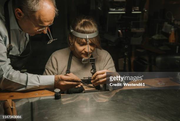 artisan and his coworker making jewellery in his workshop - man sitting at a desk craft stockfoto's en -beelden