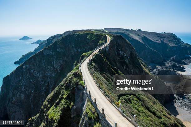 united kingdom, channel islands, road connecting the narrow isthmus of greater and little sark - channel islands england stock pictures, royalty-free photos & images