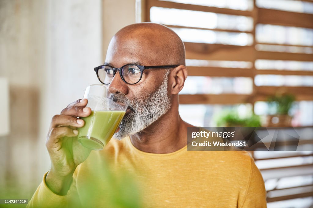 Mature businessman in office drinking a smoothie
