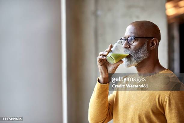mature businessman in office drinking a smoothie - healthy refreshment stock pictures, royalty-free photos & images