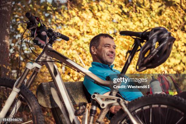 man with mountainbike having a break sitting on a bench - blank sports jersey stock pictures, royalty-free photos & images