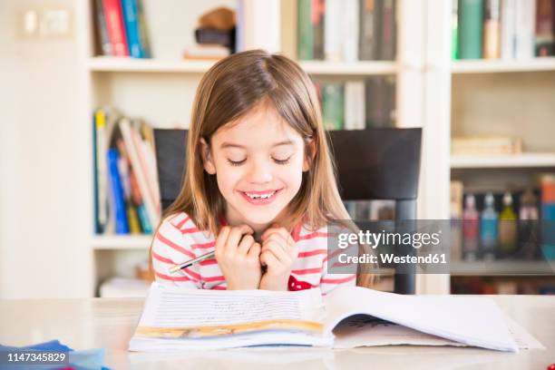 portrait of happy little girl doing homework - schulheft stock-fotos und bilder