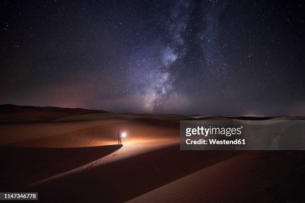 morocco, man with light at night in merzouga desert - light discovery stock-fotos und bilder