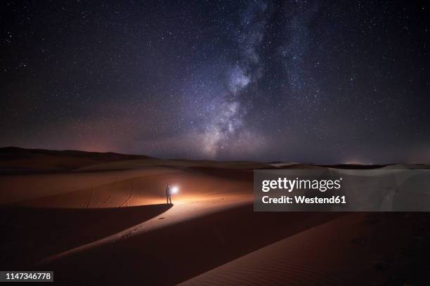 morocco, man with light at night in merzouga desert - descubrir fotografías e imágenes de stock