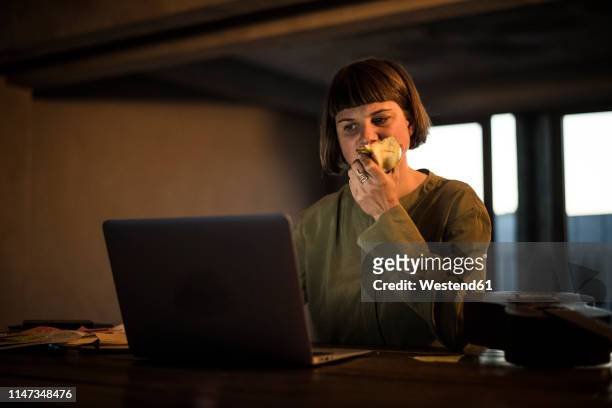 businesswoman working late, eating apple - adult female eating an apple stock pictures, royalty-free photos & images