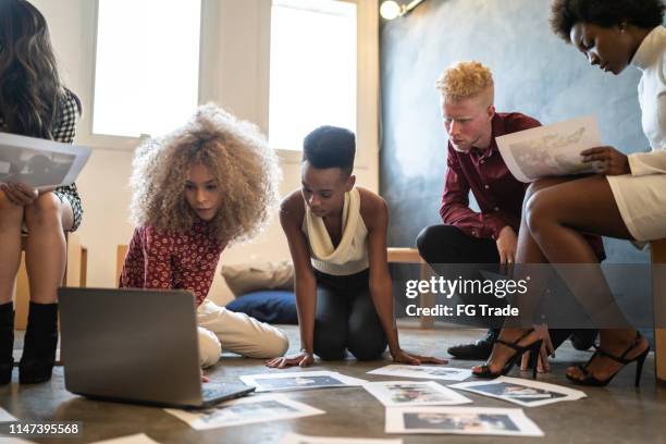 business-team diskutiert einige papiere auf dem boden im büro - internship marketing stock-fotos und bilder