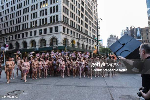 People are directed by artist Spencer Tunick to pose nude holding cut outs of nipples during a photo shoot on June 2, 2019 in New York City. Spencer...