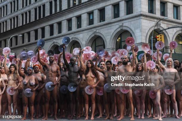 People pose nude holding cut outs of nipples during a photo shoot by artist Spencer Tunick on June 2, 2019 in New York City. Spencer Tunick staged...