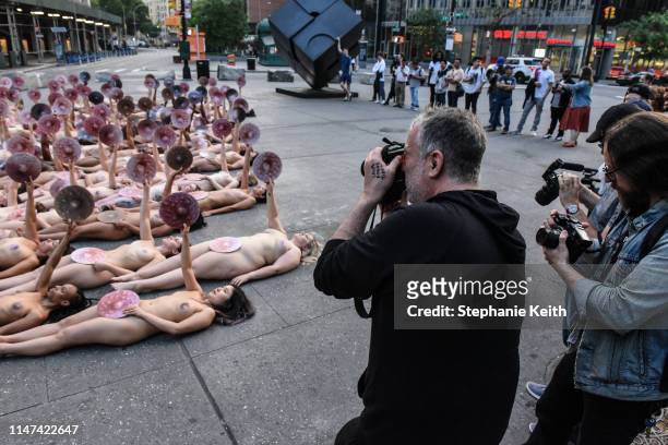 People are directed by artist Spencer Tunick to pose nude holding cut outs of nipples during a photo shoot on June 2, 2019 in New York City. Spencer...