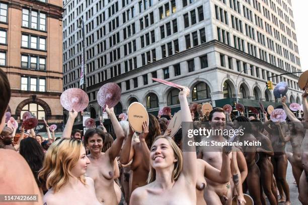 People celebrate after posing nude holding cut outs of nipples during a photo shoot by artist Spencer Tunick on June 2, 2019 in New York City....