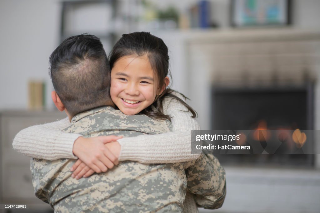 Papá militar abrazando a su hija pequeña