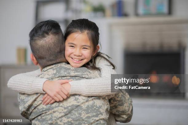 military dad hugging his young daughter - filipino family reunion stock pictures, royalty-free photos & images