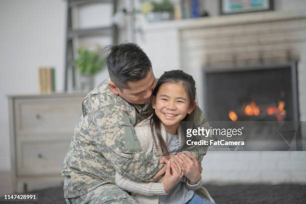 military dad hugging his young daughter - filipino family reunion stock pictures, royalty-free photos & images