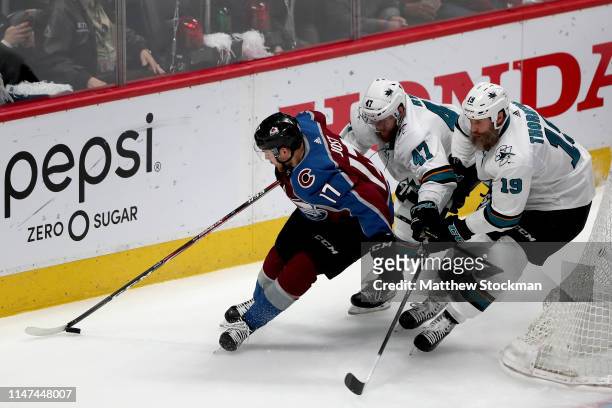 Tyson Jost of the Colorado Avalanche brings the puck out from behind the net against Joakim Ryan and Joe Thornton of the San Jose Sharks in the first...