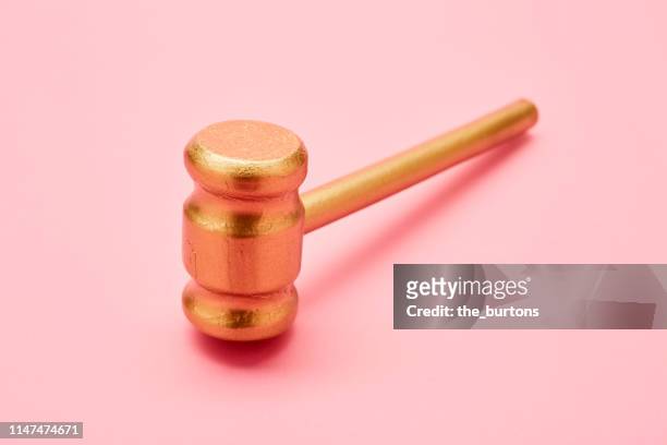 still life of a golden judge's hammer (gavel) on pink background - justice concept stock-fotos und bilder
