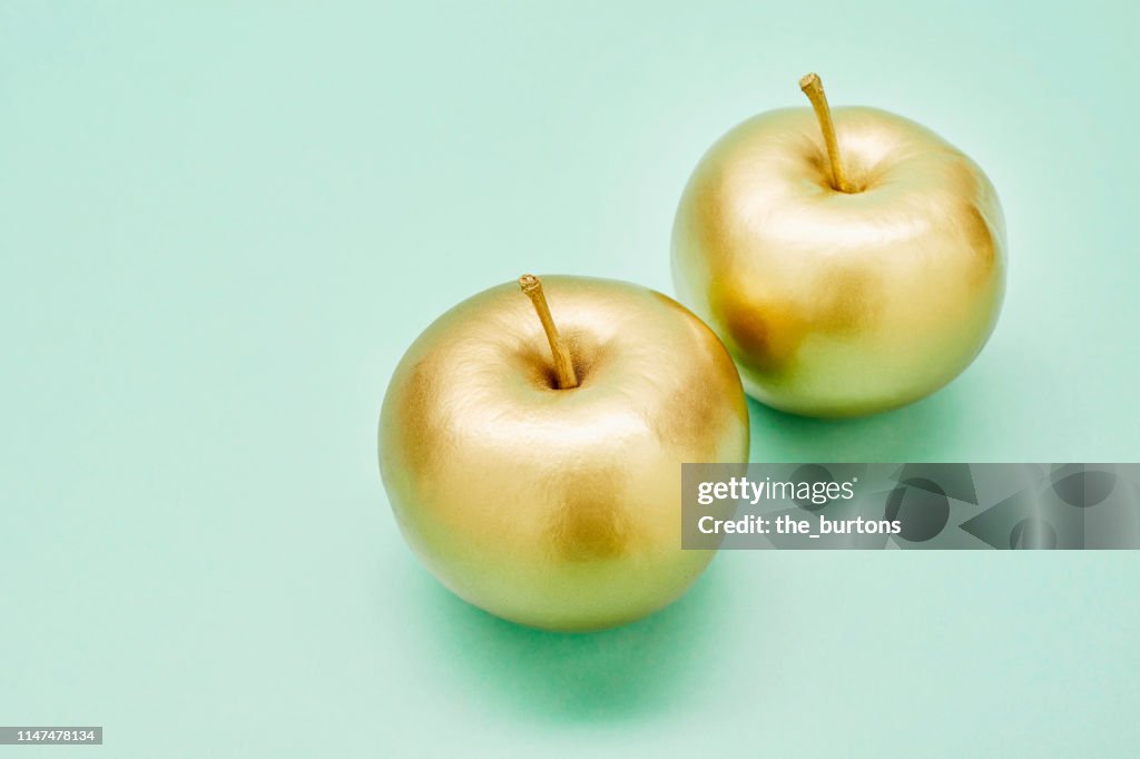 Still life of two golden apples on turquoise background
