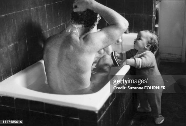 Homme prenant son bain observé par son bébé, en 1984, France.