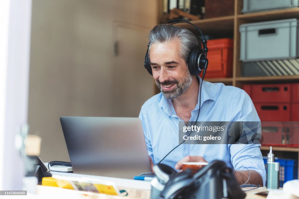 Creative man with headphones working at laptop in homeoffice