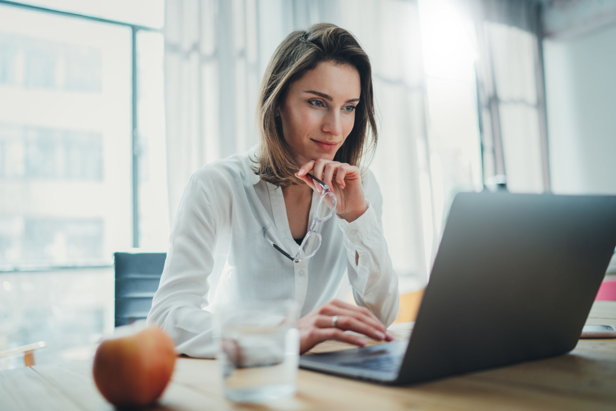 Mujer de negocios confiada trabajando en Laptop en su lugar de trabajo en la oficina moderna. Fondo borroso. Mujer de negocios confiada trabajando en Laptop en su lugar de trabajo en la oficina moderna. Fondo borroso.
