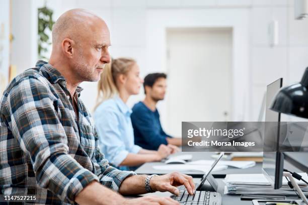 businessman working on computer with coworkers - zealand denmark stock pictures, royalty-free photos & images