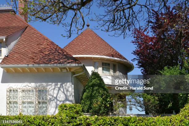 exterior view of a stucco home showing a turret architectural feature and surrounding landscaping with  trees and hedges. - architectural feature stockfoto's en -beelden