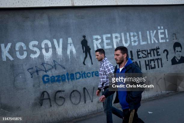 People walk past graffiti on May 3, 2019 in Pristina, Kosovo. A recent EU-backed summit failed to restart negotiations between leaders from Kosovo...