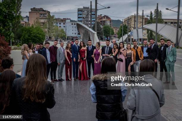 People take photographs of a graduation ceremony in front of The New Bridge on the edge of the Ibar river in the ethnic Albanian southern part of the...