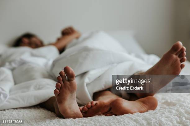 feet of a couple in a bed - stock image - foot kiss stock pictures, royalty-free photos & images