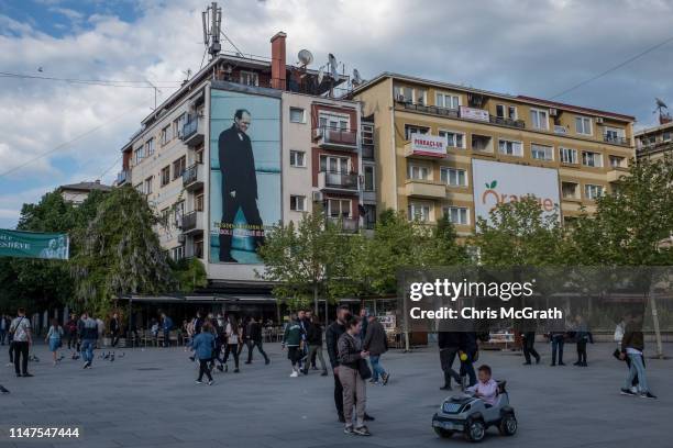 People walk underneath a large poster of the first president of the partially recognized Republic of Kosovo, Ibrahim Rugova on May 3, 2019 in...