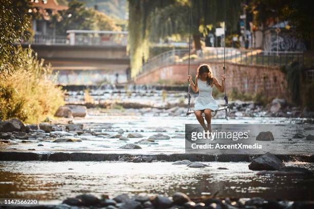 young woman swings over stream - freiburg im breisgau stock pictures, royalty-free photos & images