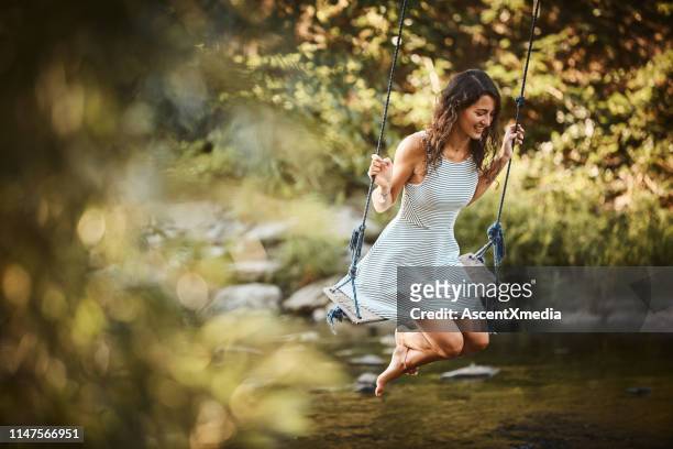 young woman swings over stream - andar de baloiço imagens e fotografias de stock