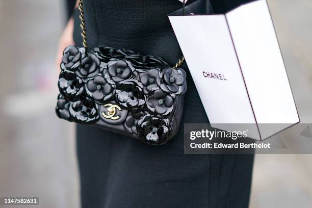 Guest wears a Chanel black camellias bag, outside the Chanel Cruise Collection 2020 At Grand Palais on May 03, 2019 in Paris, France.