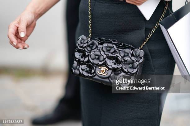 Guest wears a Chanel black camellias bag, outside the Chanel Cruise Collection 2020 At Grand Palais on May 03, 2019 in Paris, France.