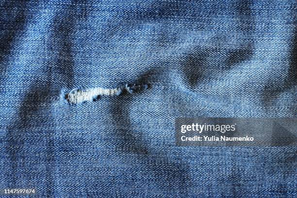 blue denim texture background, there is a hole in the fabric - denim foto e immagini stock