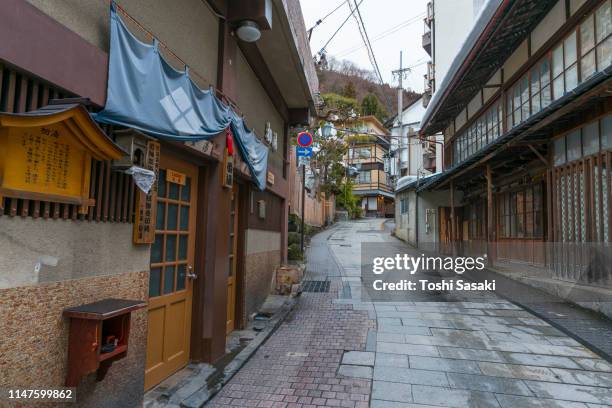 first hot spring (ichibanyu) called hatsuyu among the japanese style houses and ryokan (traditional japanese inn) along the stone pavement alley in shibu onsen town (shibu hot spring) yamanouchi, yudanaka nagano japan on feb. 20 2019. - jigokudani imagens e fotografias de stock