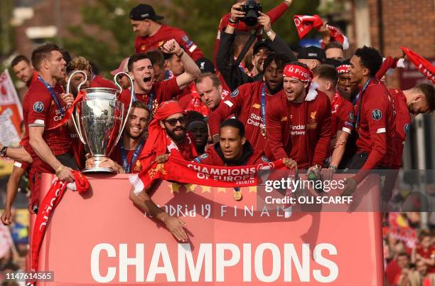 Liverpool's English midfielder James Milner holds the European Champion Clubs' Cup trophy as he stands with teammates Liverpool's English midfielder...