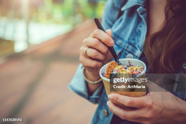 junge frau, die gesundes walzeis oder joghurt mit früchten oder beeren, keksen, süßigkeiten und minze isst - gefrorener joghurt stock-fotos und bilder