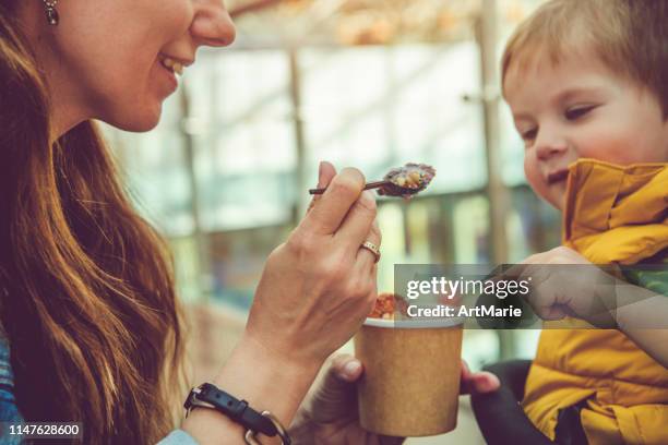 young woman giving his son healthy rolled ice-cream or yogurt with fruits or berries, cookies, candy and mint - ice cream sundae stock pictures, royalty-free photos & images