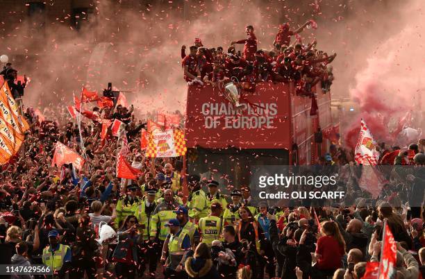 Football fans line the streets to see the Liverpool football team take part in an open-top bus parade around Liverpool, north-west England on June 2...