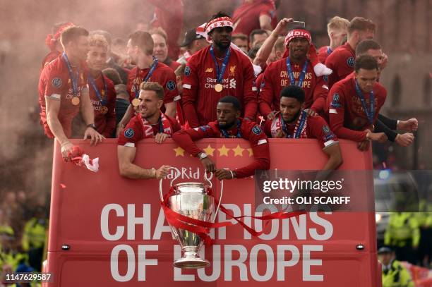 Liverpool's English midfielder Jordan Henderson and Liverpool's Dutch midfielder Georginio Wijnaldum hold the European Champion Clubs' Cup trophy,...