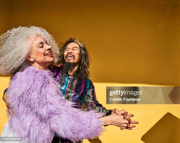 colourful studio portrait of a senior man and woman - couple celebrating imagens e fotografias de stock