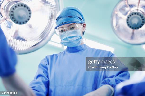 surgeon performing operation in operating room - doctor reaching stock pictures, royalty-free photos & images