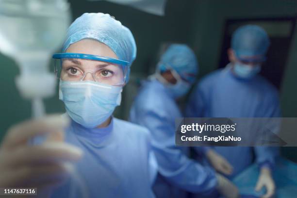 doctor checking iv in operating room - doctor reaching stock pictures, royalty-free photos & images