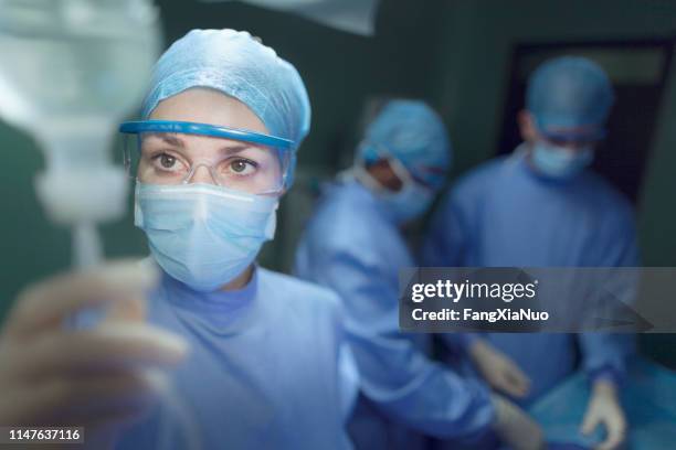 doctor checking iv in operating room - anesthesiologist stock pictures, royalty-free photos & images