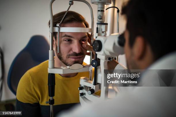 jeunes hommes ayant un examen oculaire au bureau de l’ophtalmologiste. - eye men photos et images de collection