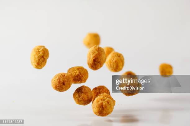 multi taste peanuts bouncing on white background captured with high speed sync."n - seasoning mid air stock pictures, royalty-free photos & images