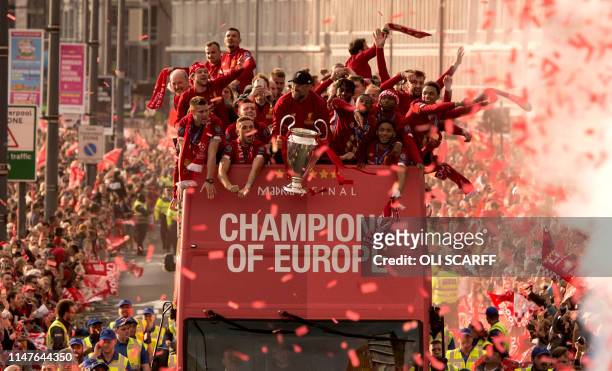 Liverpool's German manager Jurgen Klopp holds the European Champion Clubs' Cup trophy as he stands with his players during an open-top bus parade...