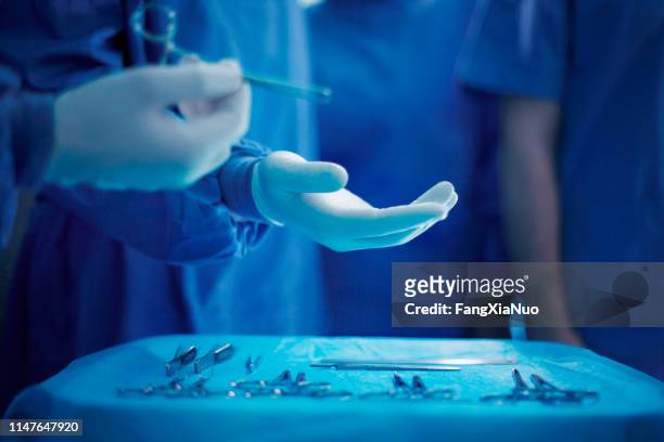 handing doctor surgical tool in operating room - doctor reaching stock pictures, royalty-free photos & images
