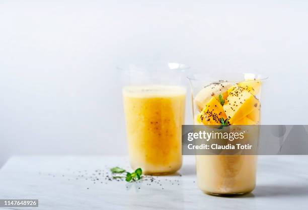 two glasses of banana and mango smoothie on white background - mango shake stock pictures, royalty-free photos & images